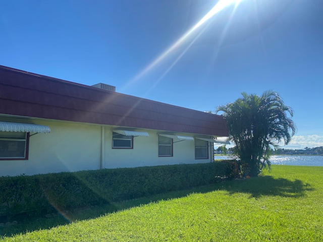 view of side of property with a water view and a yard