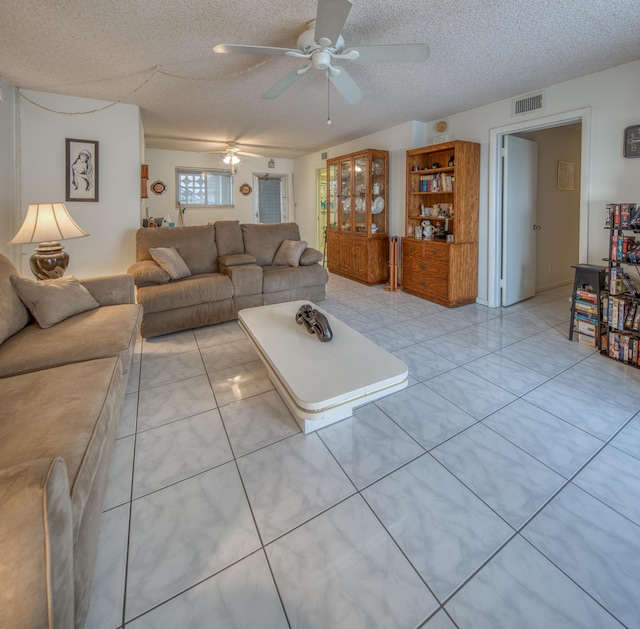 living room with a ceiling fan, visible vents, a textured ceiling, and light tile patterned floors