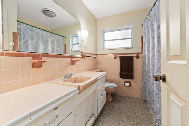 bathroom with vanity, toilet, and tile walls