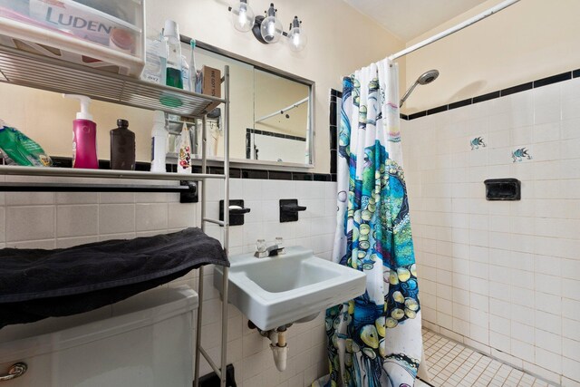 bathroom with tile patterned floors, a shower with curtain, sink, and tile walls