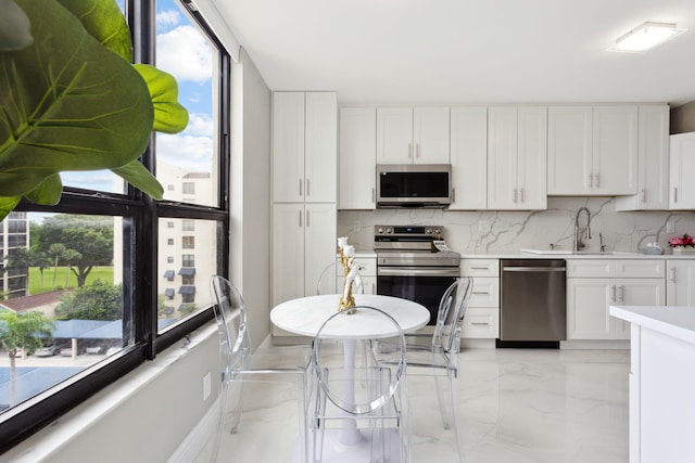 kitchen featuring tasteful backsplash, appliances with stainless steel finishes, sink, and white cabinetry