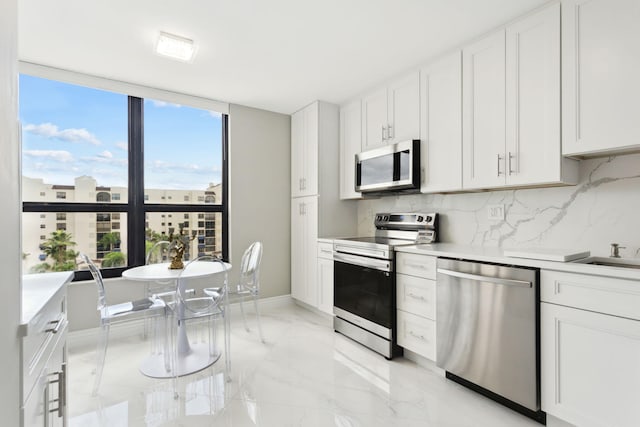 kitchen featuring backsplash, appliances with stainless steel finishes, a wealth of natural light, and white cabinetry