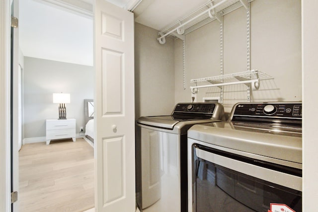 clothes washing area featuring light hardwood / wood-style floors and washing machine and clothes dryer