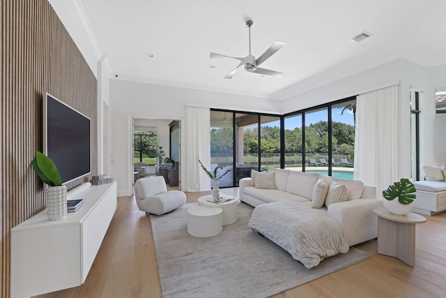 living room featuring light wood-type flooring, ceiling fan, and crown molding