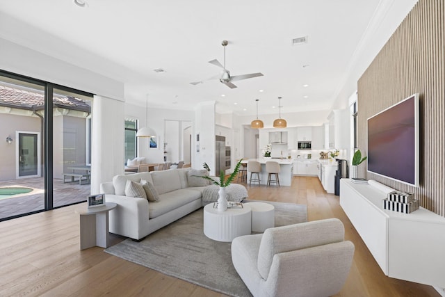 living room with ceiling fan, crown molding, and light hardwood / wood-style floors