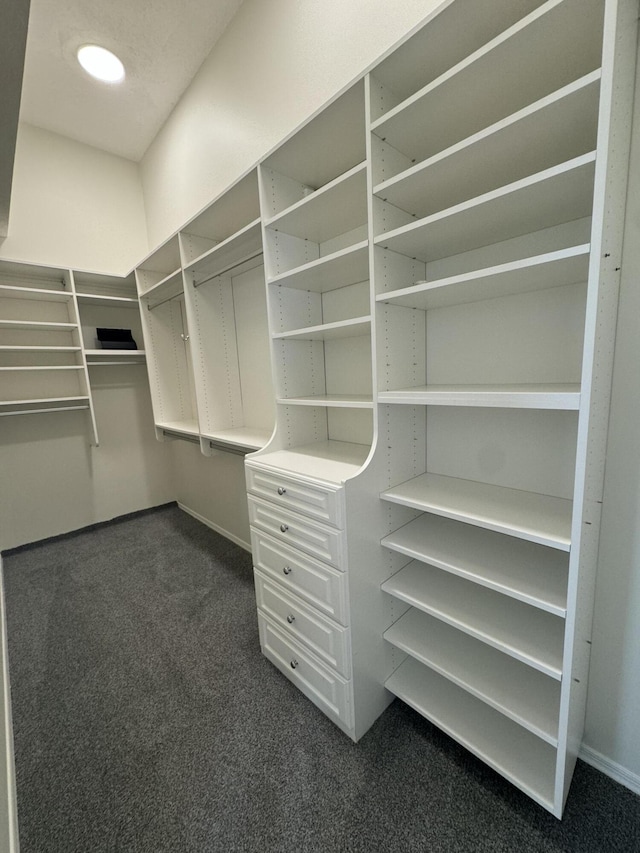 walk in closet featuring dark carpet