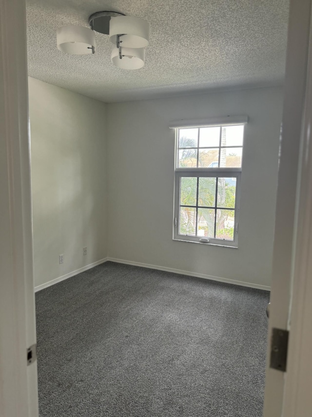 carpeted empty room featuring a textured ceiling