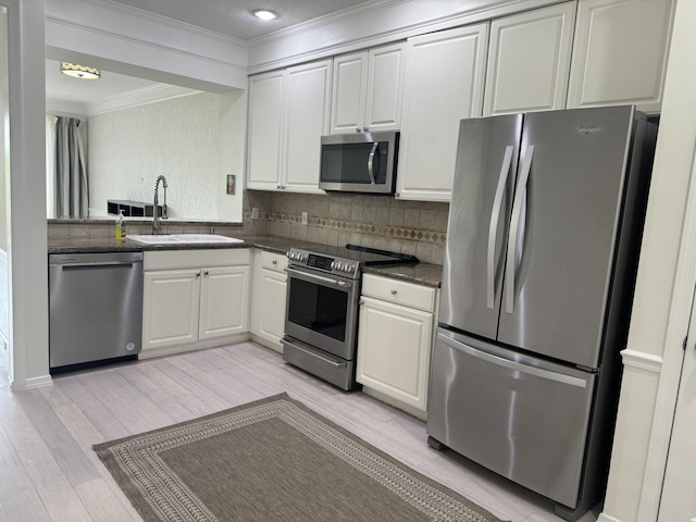 kitchen with sink, white cabinetry, light hardwood / wood-style flooring, backsplash, and appliances with stainless steel finishes