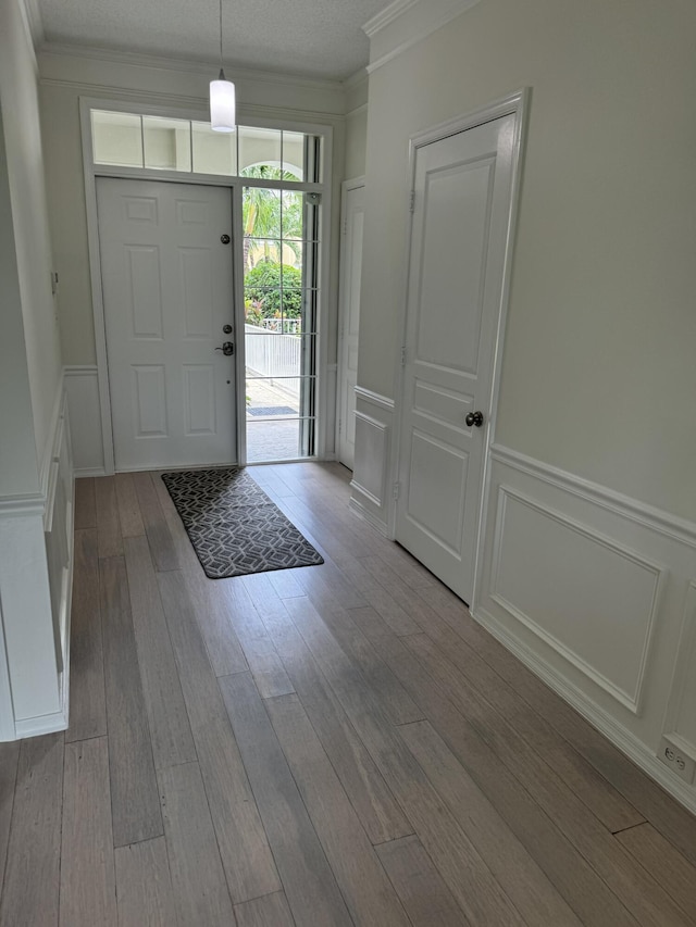 foyer entrance featuring a textured ceiling, crown molding, and light hardwood / wood-style floors