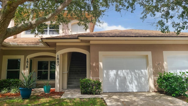 entrance to property featuring stucco siding, concrete driveway, and a garage