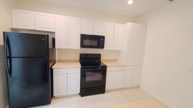 kitchen with light tile patterned floors, light countertops, white cabinets, black appliances, and baseboards