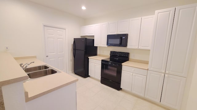 kitchen with light tile patterned floors, light countertops, white cabinets, black appliances, and a sink
