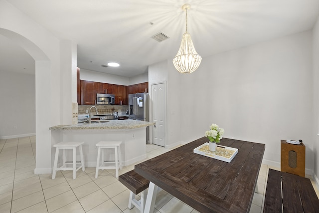 tiled dining space with a notable chandelier and sink