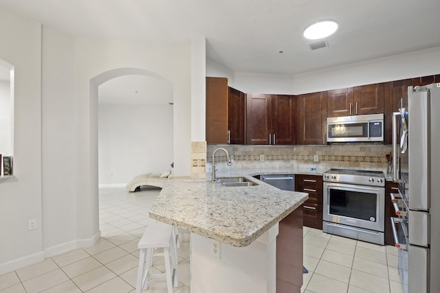 kitchen with a breakfast bar, sink, kitchen peninsula, backsplash, and appliances with stainless steel finishes