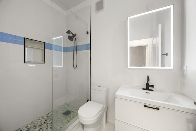 bathroom featuring tiled shower, vanity, and toilet