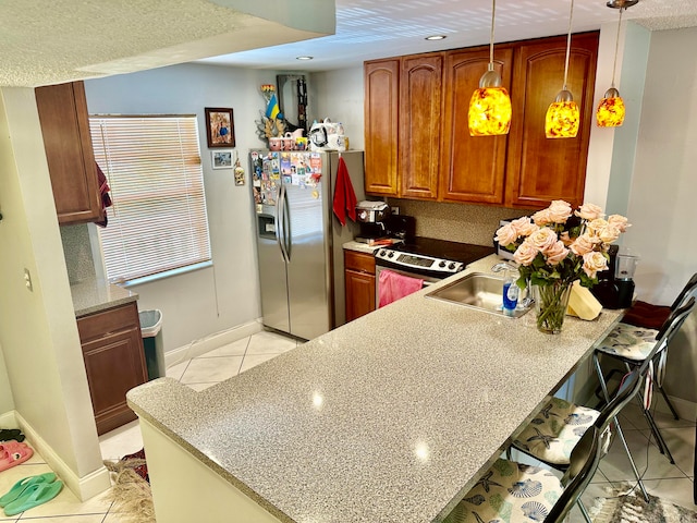 kitchen with appliances with stainless steel finishes, light tile patterned floors, a breakfast bar area, and pendant lighting