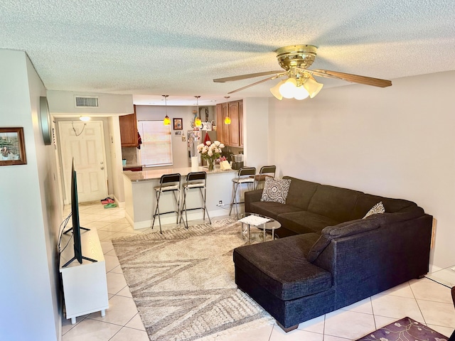 living room with ceiling fan, light tile patterned floors, and a textured ceiling