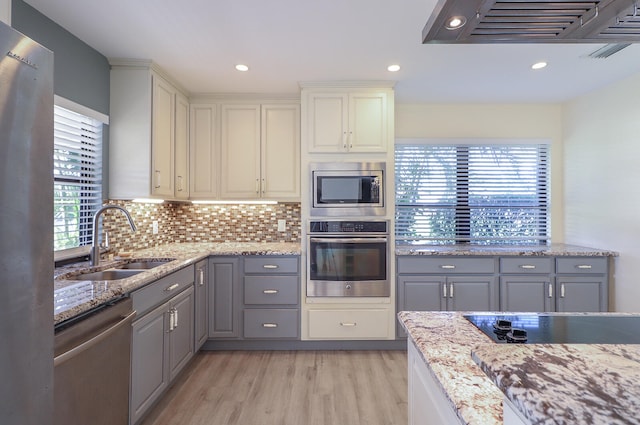 kitchen with appliances with stainless steel finishes, light hardwood / wood-style floors, a healthy amount of sunlight, and sink