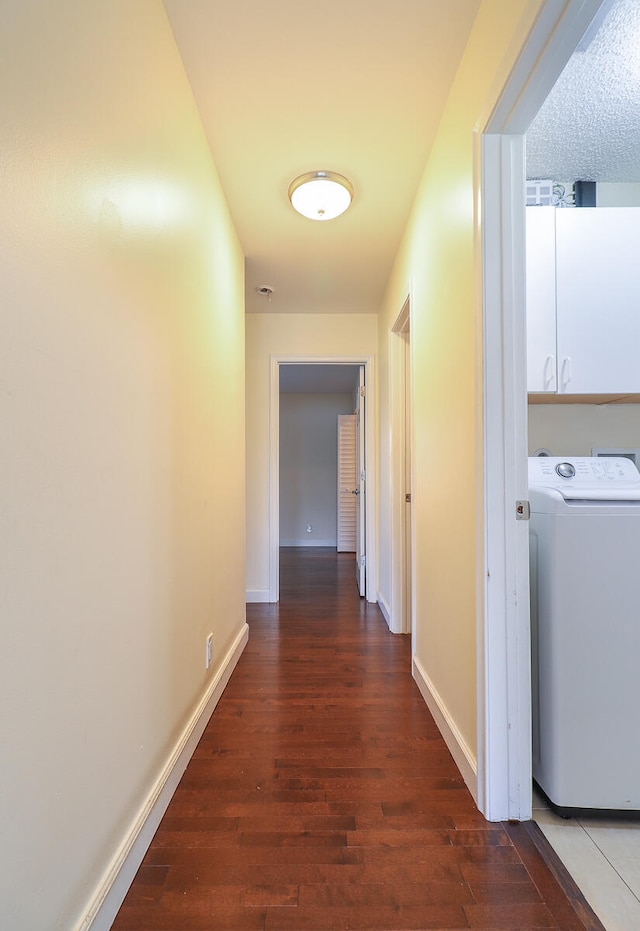 corridor with dark wood-type flooring and washer / clothes dryer