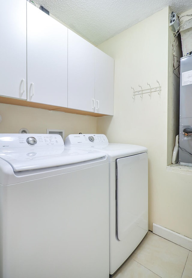 laundry area with separate washer and dryer, light tile patterned floors, cabinets, and a textured ceiling