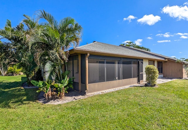 rear view of property with a yard and a sunroom