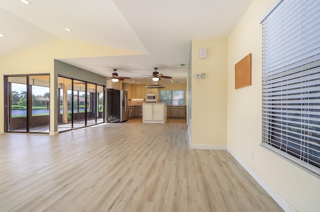 unfurnished living room featuring vaulted ceiling, light hardwood / wood-style flooring, and ceiling fan