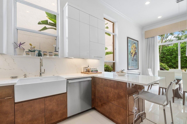 kitchen featuring decorative backsplash, white cabinets, a healthy amount of sunlight, and stainless steel dishwasher