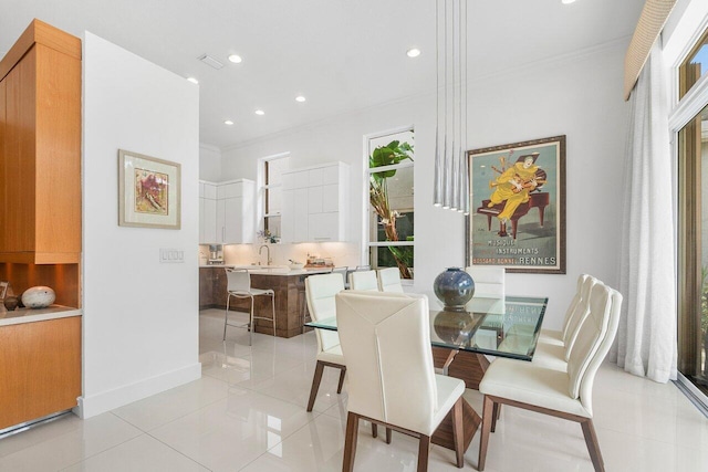 dining area with sink, ornamental molding, and light tile patterned floors