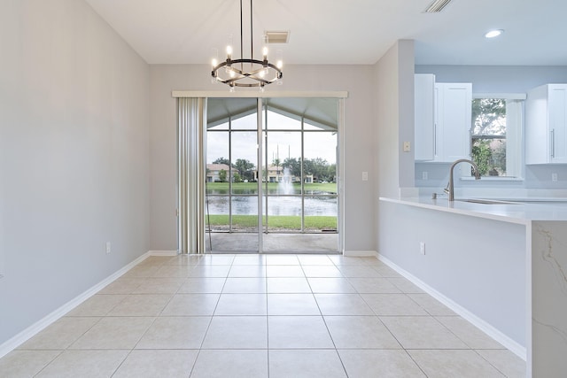 unfurnished dining area with a notable chandelier, light tile patterned flooring, and sink