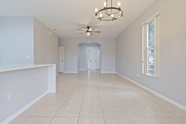 spare room with ceiling fan with notable chandelier, plenty of natural light, and light tile patterned floors