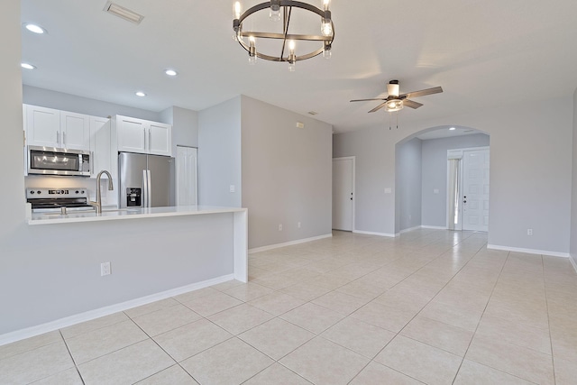 kitchen with white cabinets, sink, light tile patterned floors, appliances with stainless steel finishes, and ceiling fan with notable chandelier