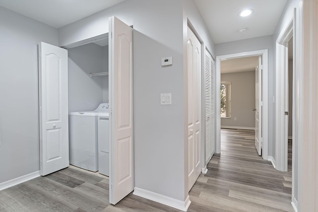 laundry area with separate washer and dryer and light hardwood / wood-style floors