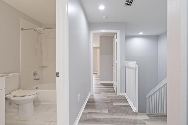 bathroom with wood-type flooring,  shower combination, and toilet