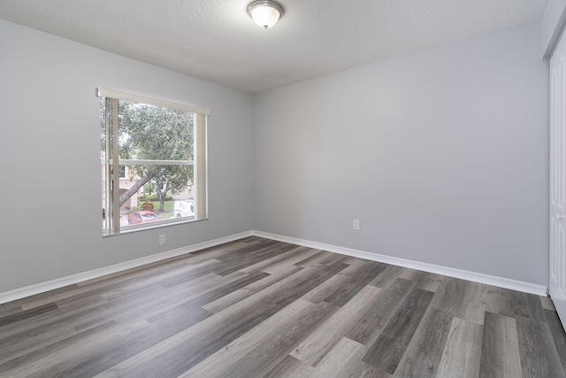 unfurnished room with a textured ceiling and dark hardwood / wood-style flooring