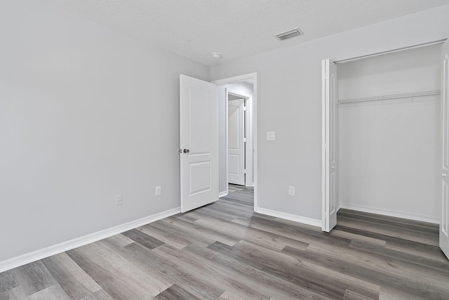 unfurnished bedroom featuring a closet, hardwood / wood-style floors, and a textured ceiling