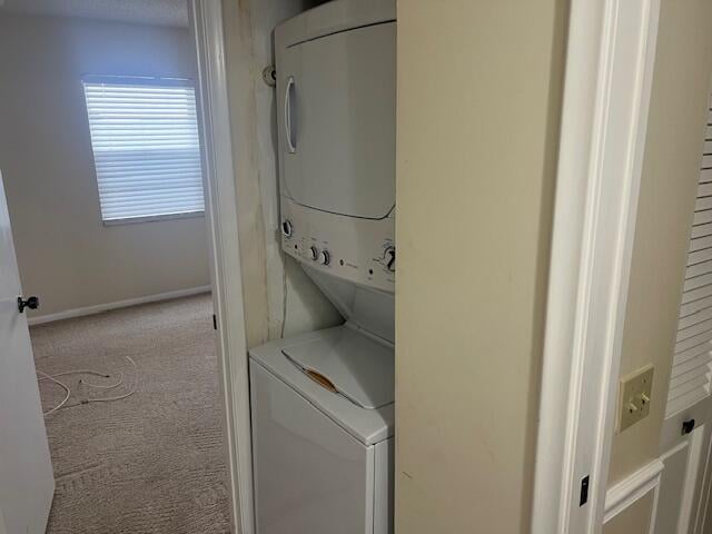 clothes washing area featuring stacked washer / dryer and carpet