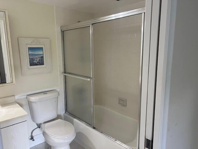 full bathroom with shower / bath combination with glass door, vanity, tile patterned flooring, and toilet