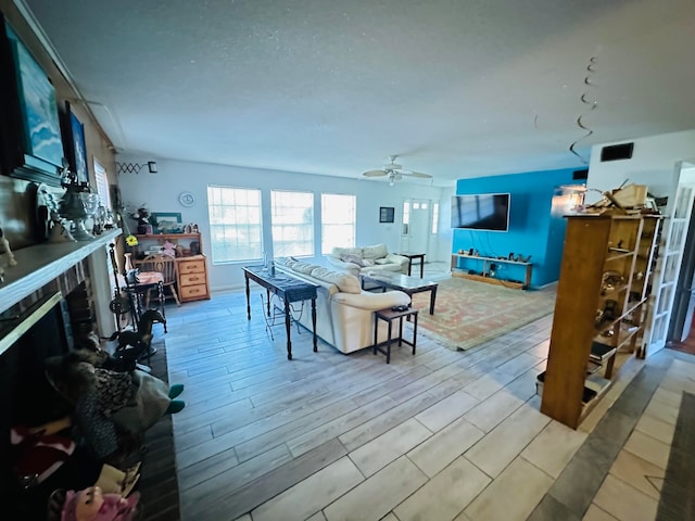 living room featuring ceiling fan, light hardwood / wood-style floors, and a fireplace