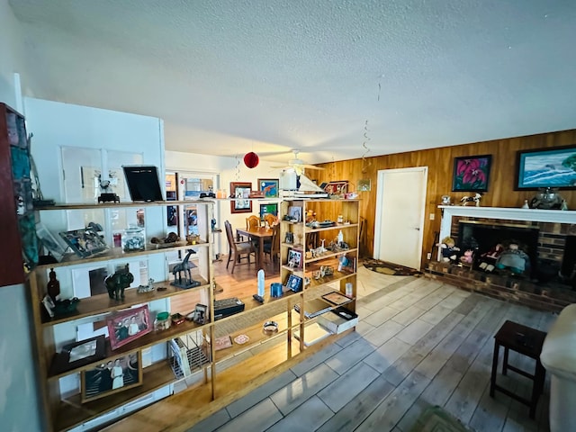 living room with ceiling fan, wood walls, and wood-type flooring