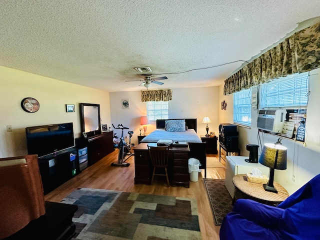 living room featuring ceiling fan, cooling unit, wood-type flooring, and a textured ceiling