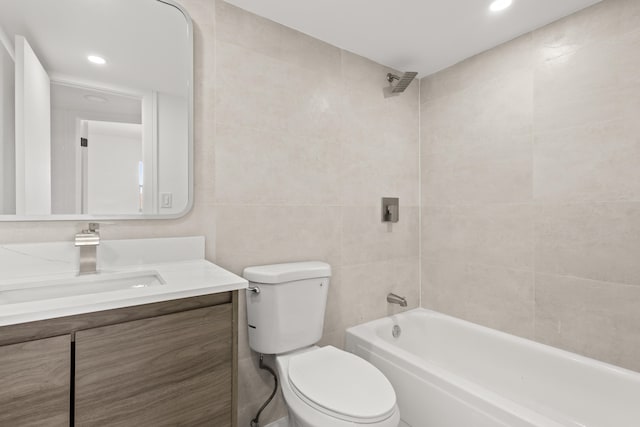 full bathroom with tiled shower / bath, vanity, tile walls, and toilet