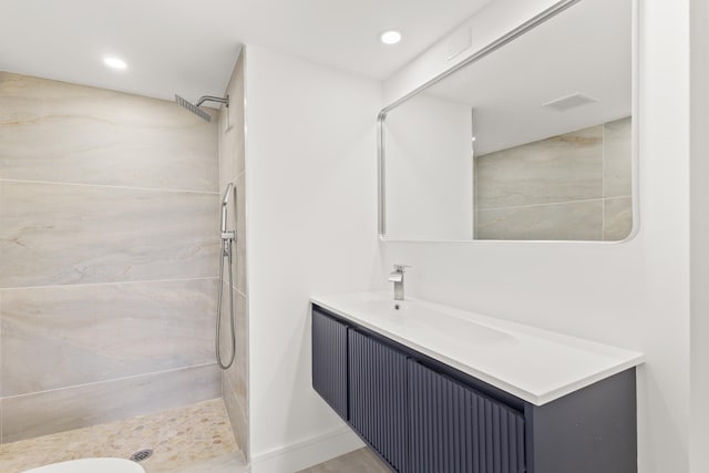 bathroom featuring a tile shower and vanity