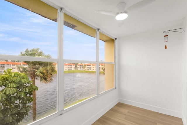 unfurnished sunroom with ceiling fan, plenty of natural light, and a water view