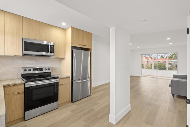 kitchen featuring light wood-type flooring, light brown cabinetry, stainless steel appliances, and tasteful backsplash