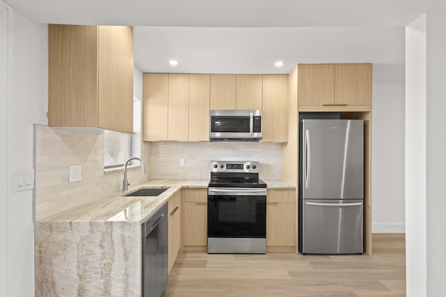 kitchen featuring light brown cabinets, sink, tasteful backsplash, stainless steel appliances, and light hardwood / wood-style floors