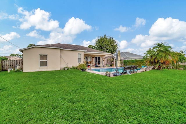 rear view of property featuring a fenced in pool, a patio area, and a yard