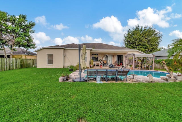 rear view of property featuring a yard, a fenced in pool, and a patio area