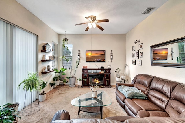 carpeted living room featuring ceiling fan and a textured ceiling