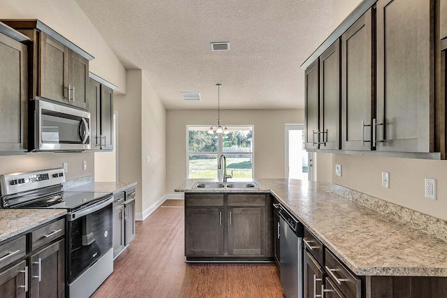 kitchen with a peninsula, appliances with stainless steel finishes, a sink, and visible vents