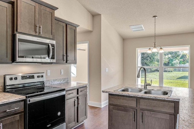 kitchen with dark wood-style flooring, stainless steel appliances, light countertops, visible vents, and a sink